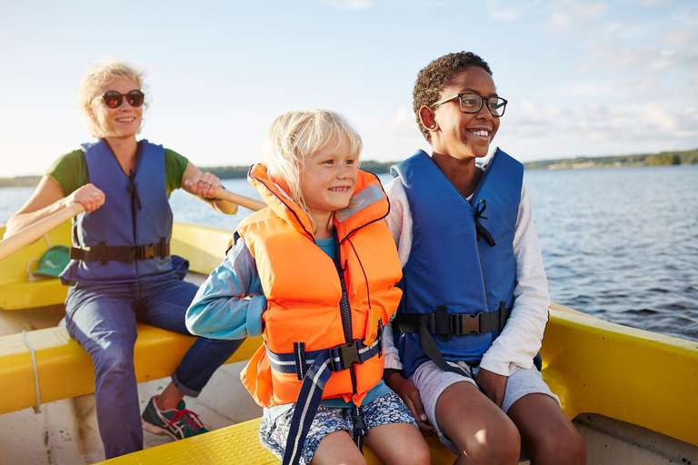 Woman and two kids wearing life jackets in canoe, know Florida life jacket laws concept. 