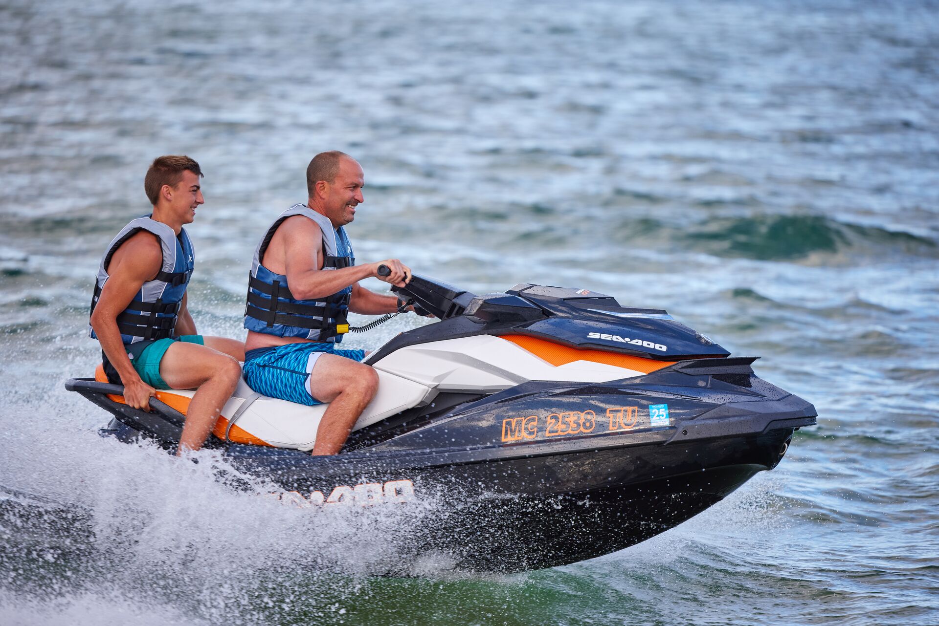 Smiling man and boy on PWC, know life jacket laws by state concept. 