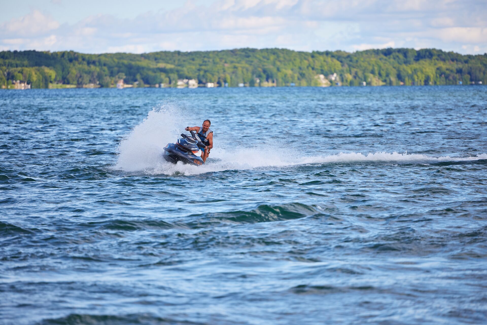 Riders on a PWC in the distance on a lake, how old to get a jet ski license concept. 
