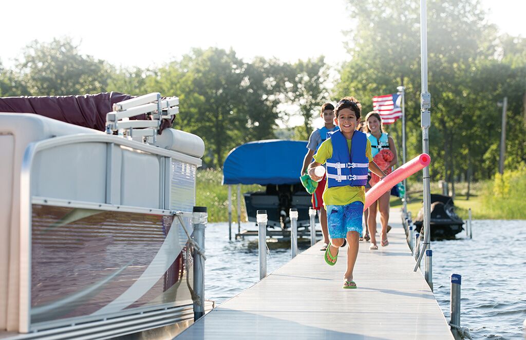 Kid runs on dock toward pontoon boat, know the parts of a pontoon boat concept. 